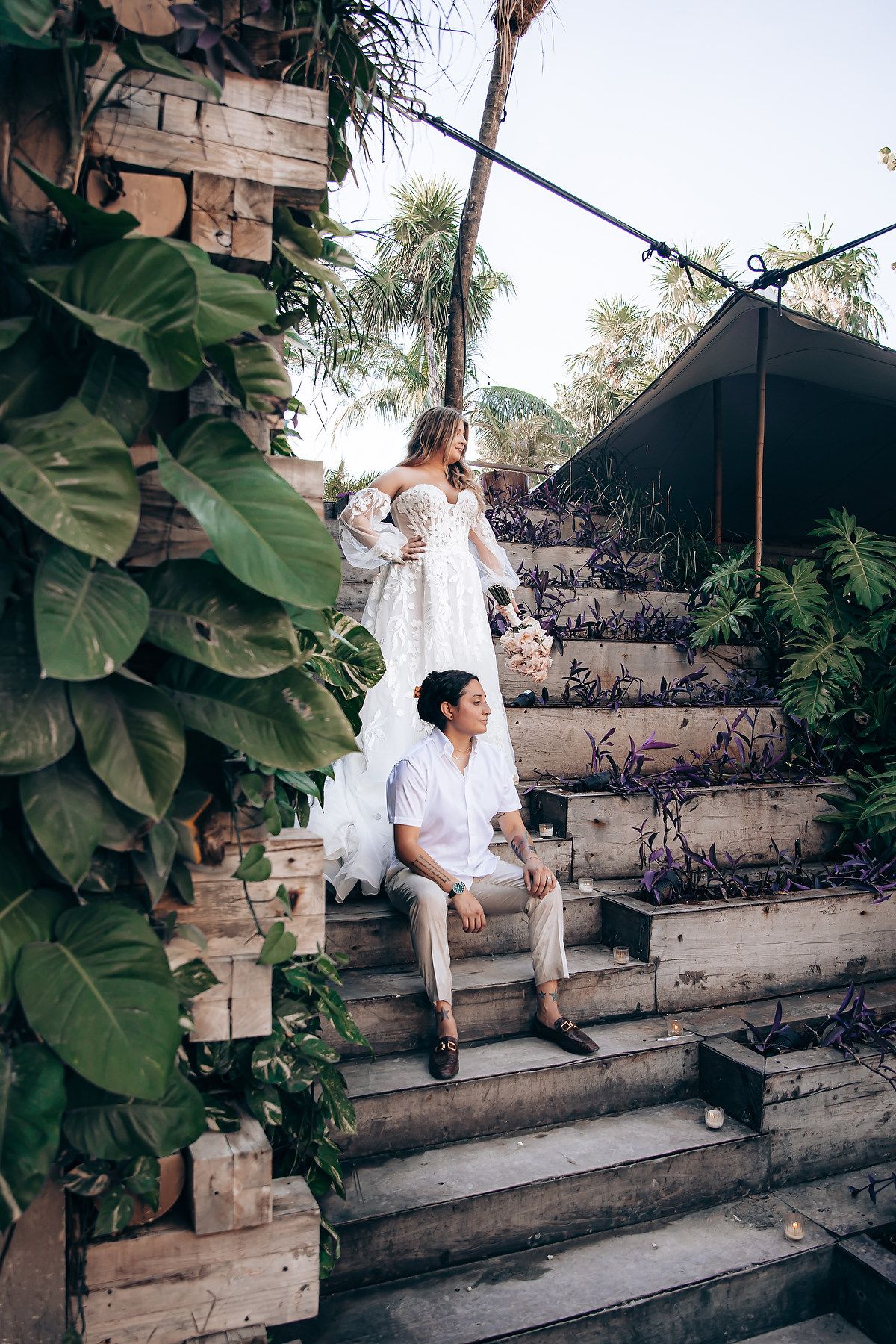 Rustic wooden steps adorned with tropical foliage in an outdoor garden setting.