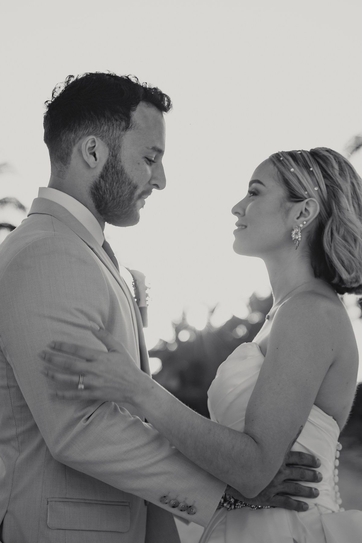 Black and white portrait of bride and groom embracing tenderly at their tropical wedding.