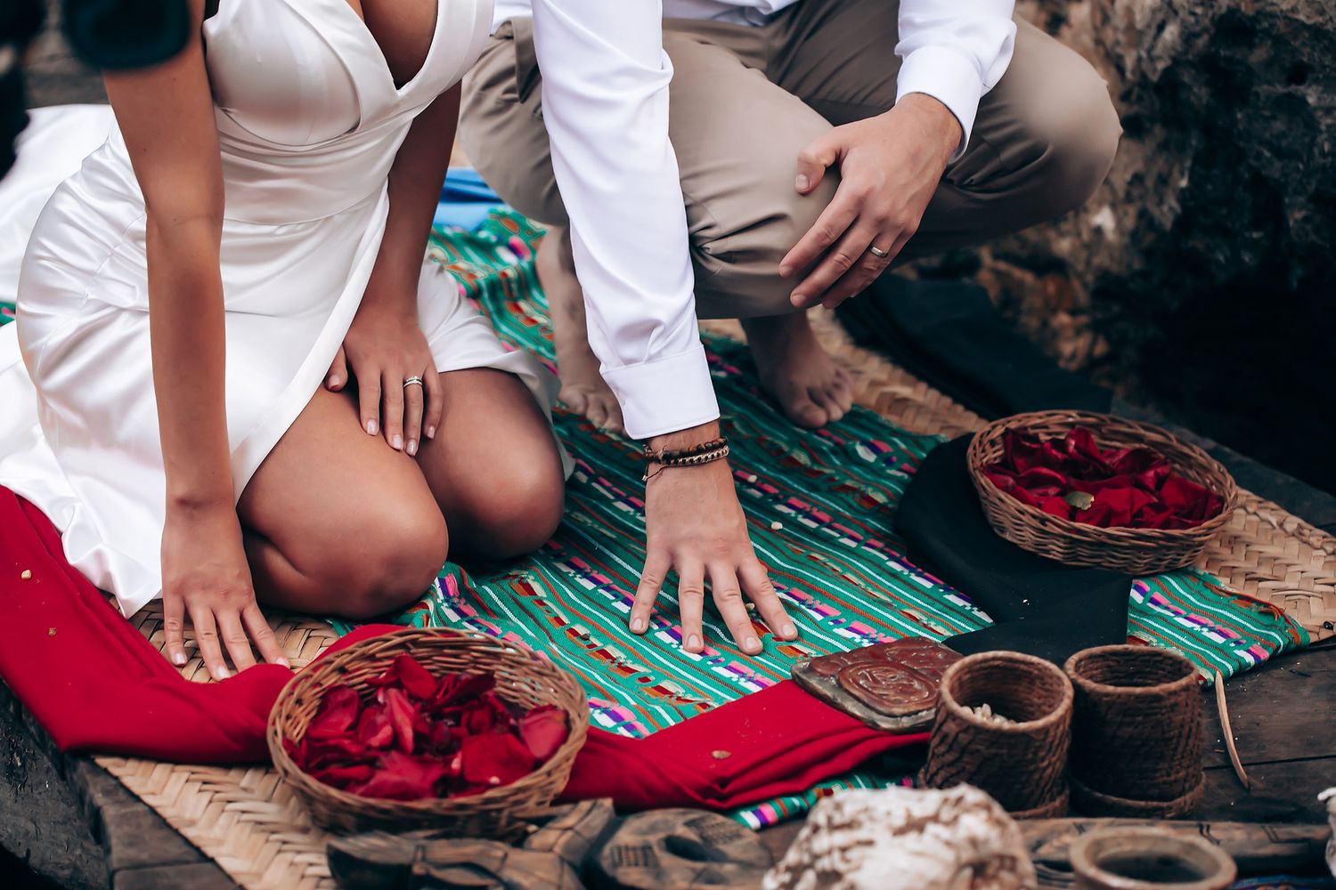 Wedding ceremony setup with red and natural textiles in a cave-like setting.