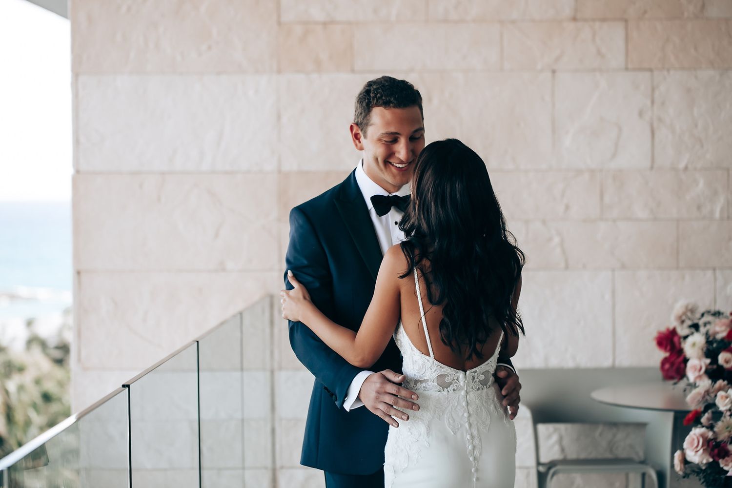 Romantic first look moment between newlyweds against stone wall backdrop.