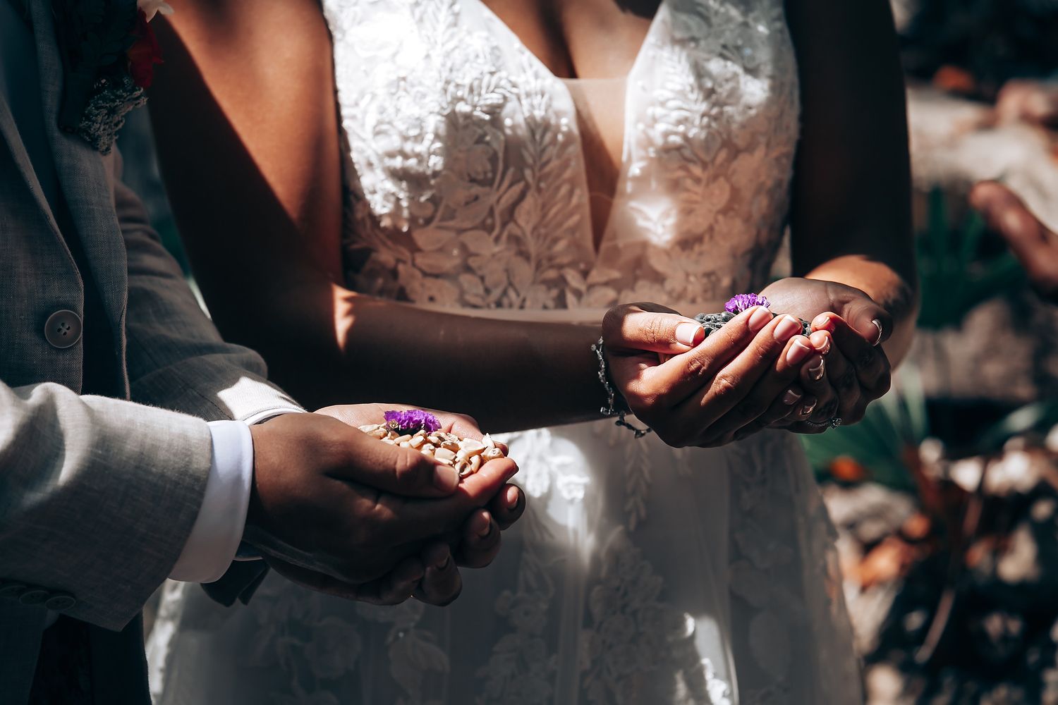 Close-up of hands during a wedding ceremony ritual in an outdoor setting.