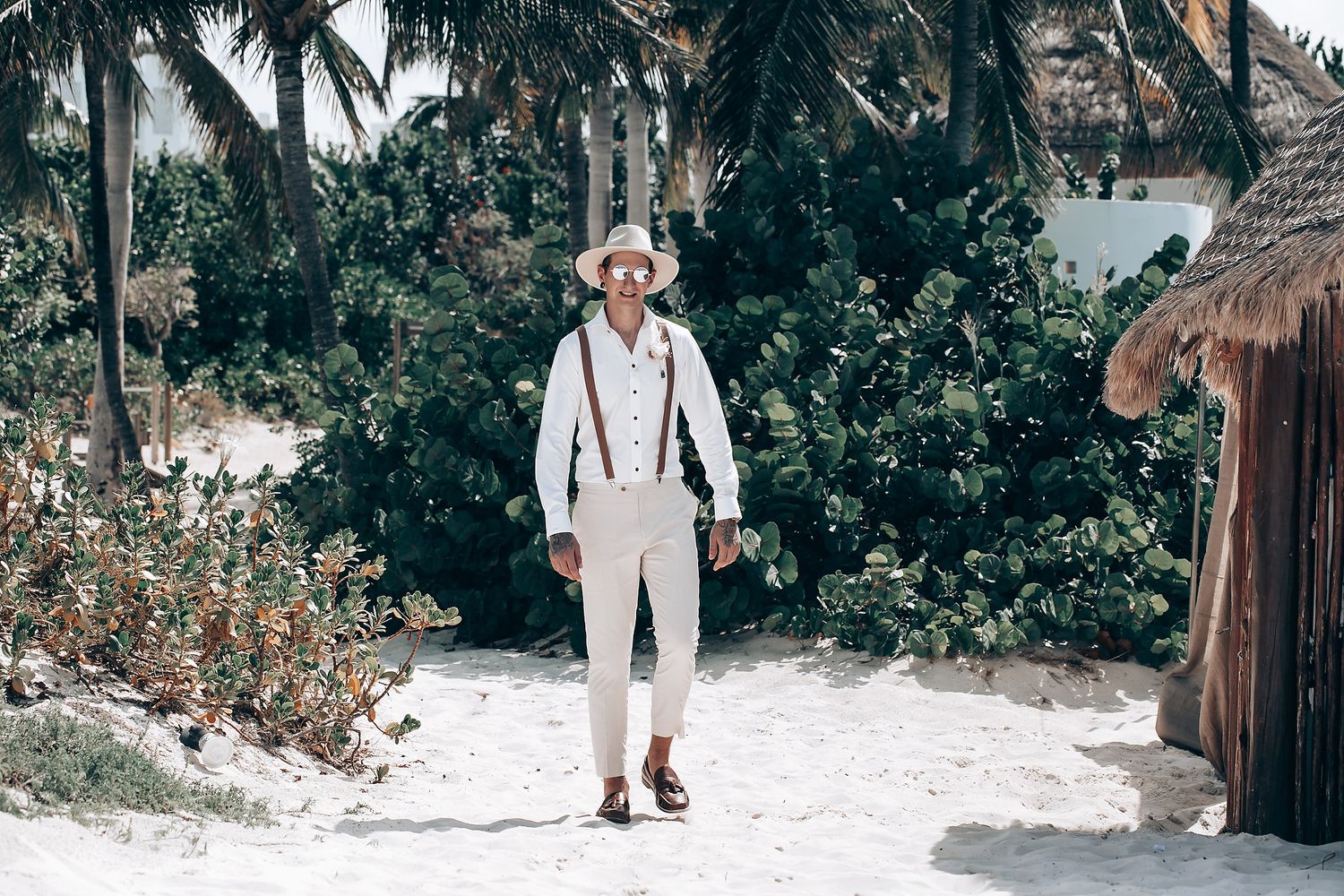 Wedding guests walking through a snowy tropical setting with palm trees and white decor.
