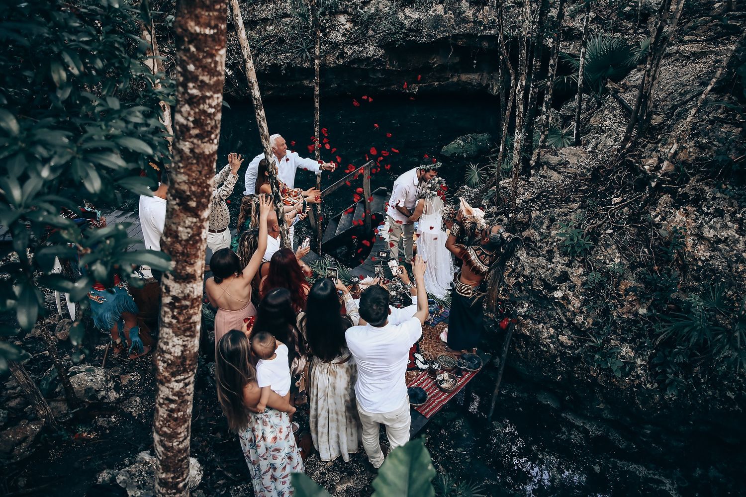 People gather around a natural cenote entrance in the Yucatan jungle for a ceremonial event.