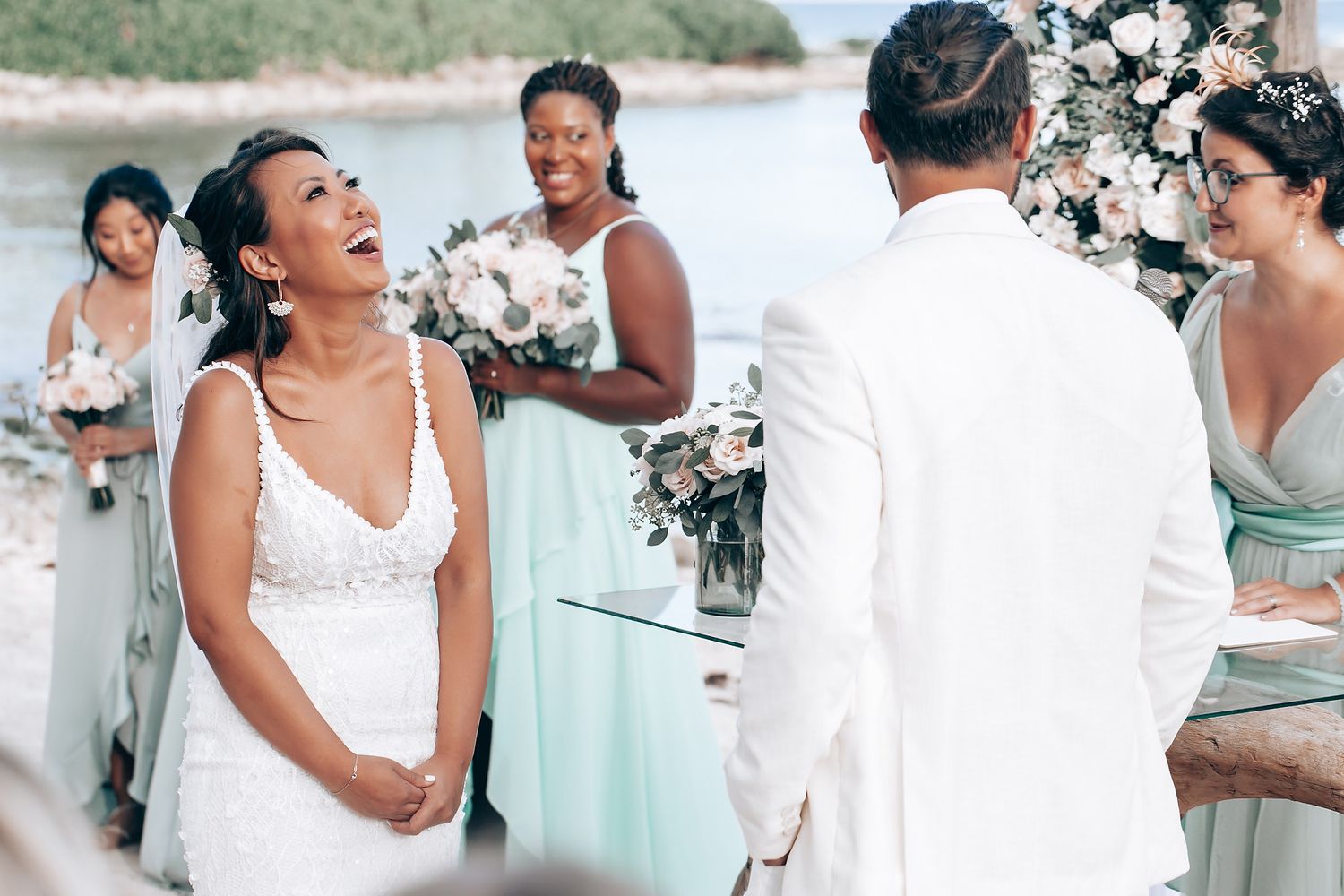 Wedding party in white and mint green attire celebrating on a bright sunny day.