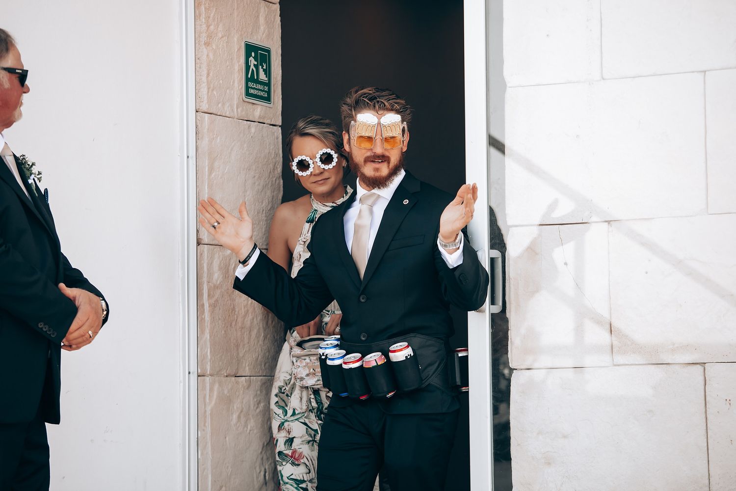 Wedding guests mingling in a modern venue hallway with white walls.