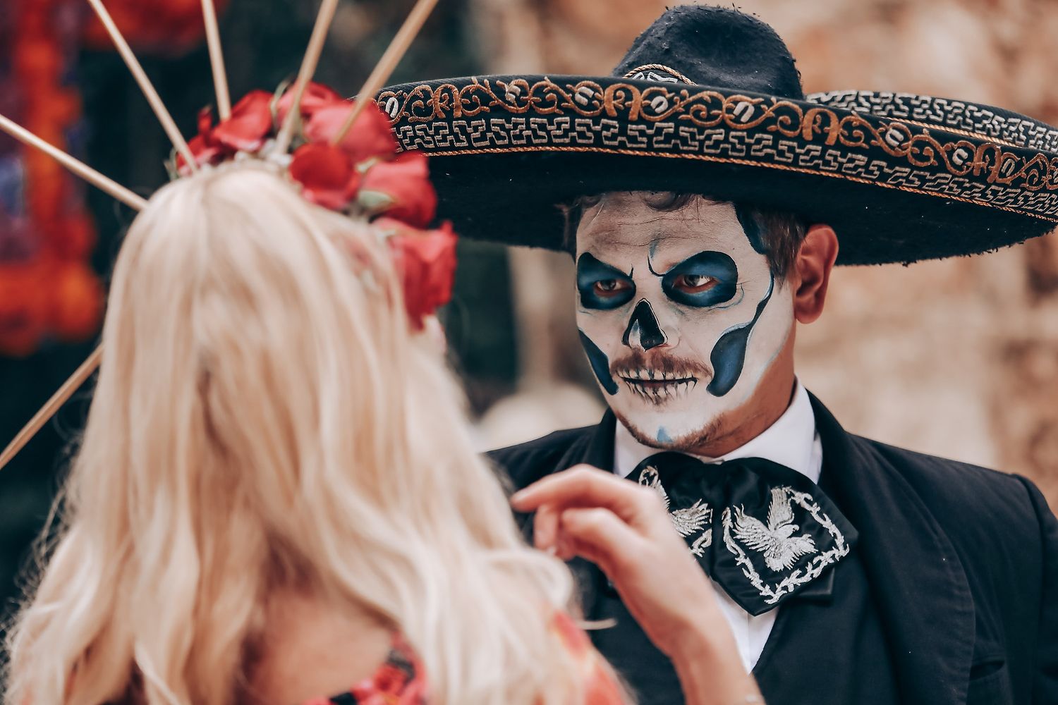 Close-up of people in Day of the Dead themed costumes with skull makeup and traditional Mexican attire.
