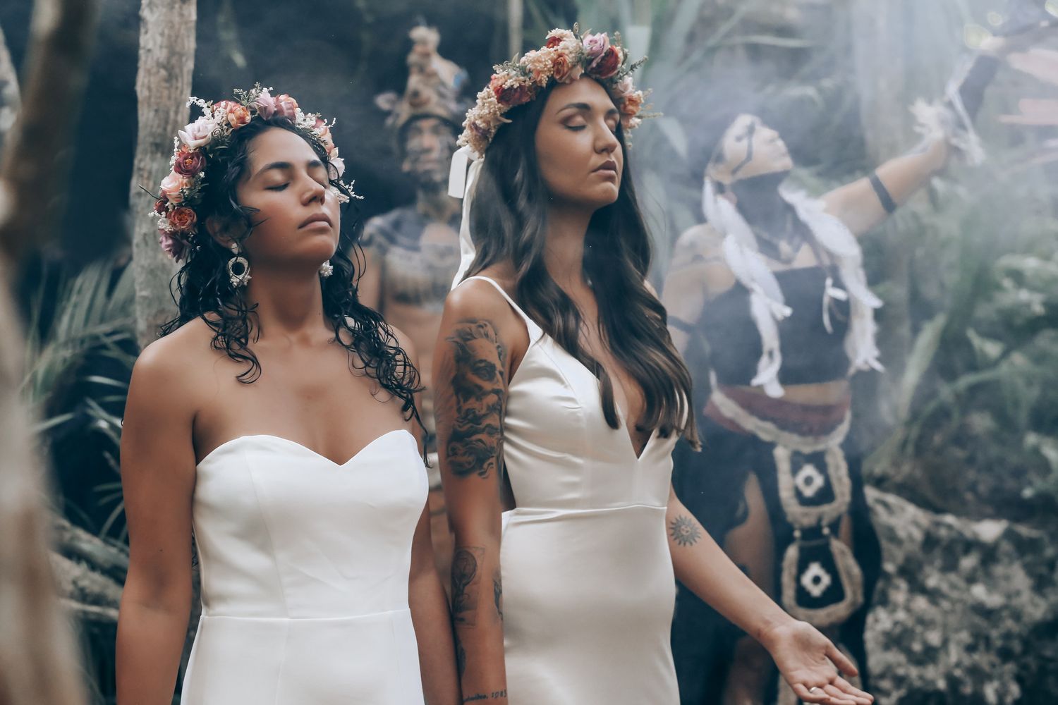 Wedding party members in white dresses pose together in an outdoor garden setting.
