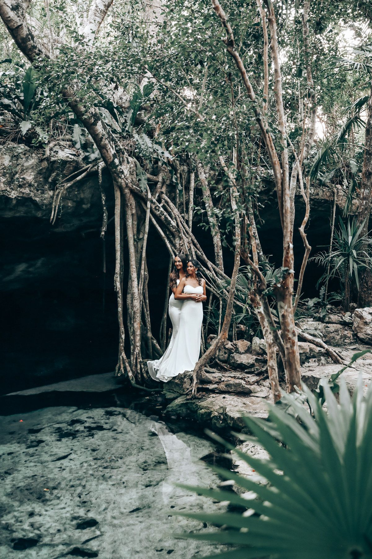 White dress against natural jungle backdrop with hanging vines near a cenote.