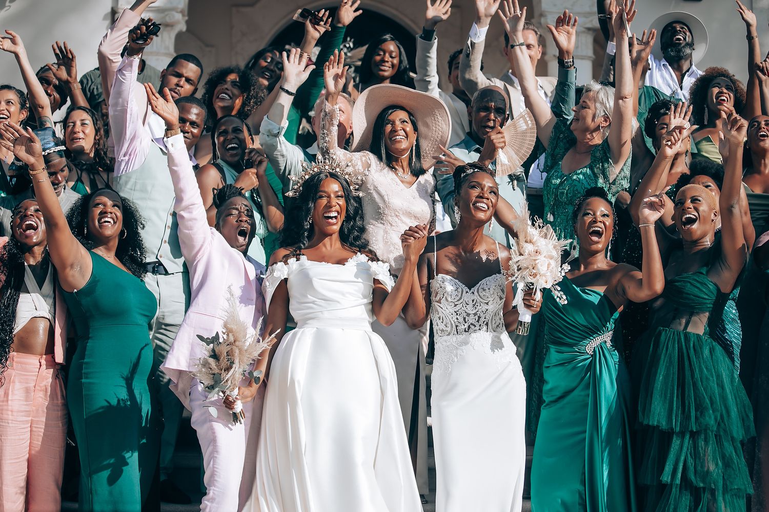 Wedding celebration with guests in emerald green and white attire cheering together.