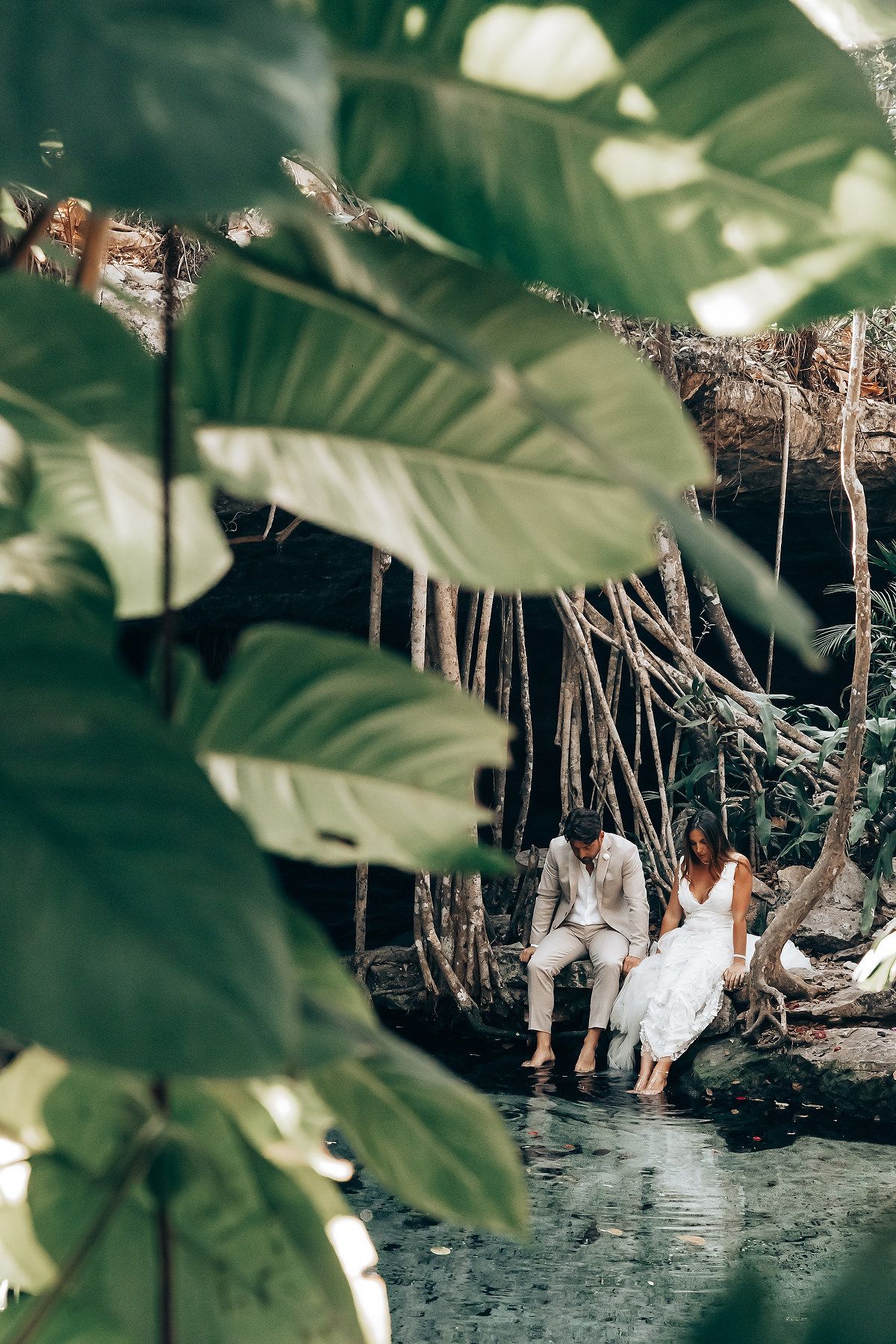 A romantic cenote photoshoot with tropical foliage framing the scene.