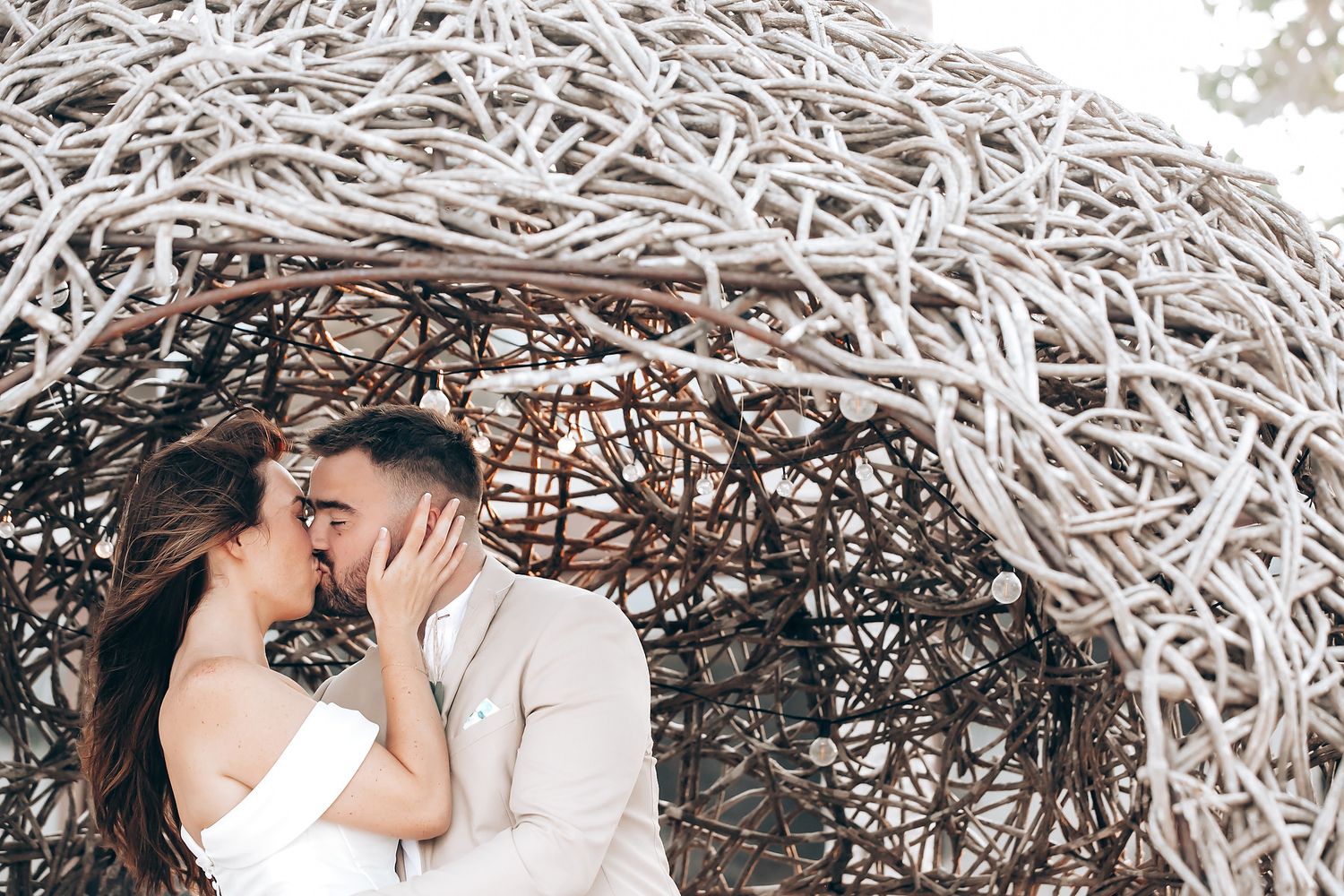 Romantic couple sharing intimate moments in a cozy outdoor setting with a white woven backdrop.