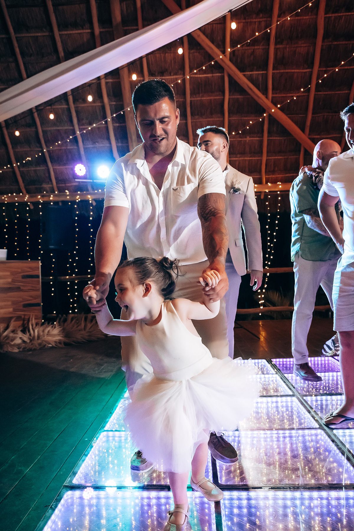 Dancers twirling on an illuminated LED dance floor with string lights creating a magical atmosphere.