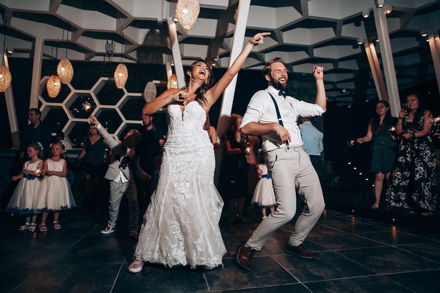 Wedding reception dance floor with guests dancing under geometric ceiling decorations.