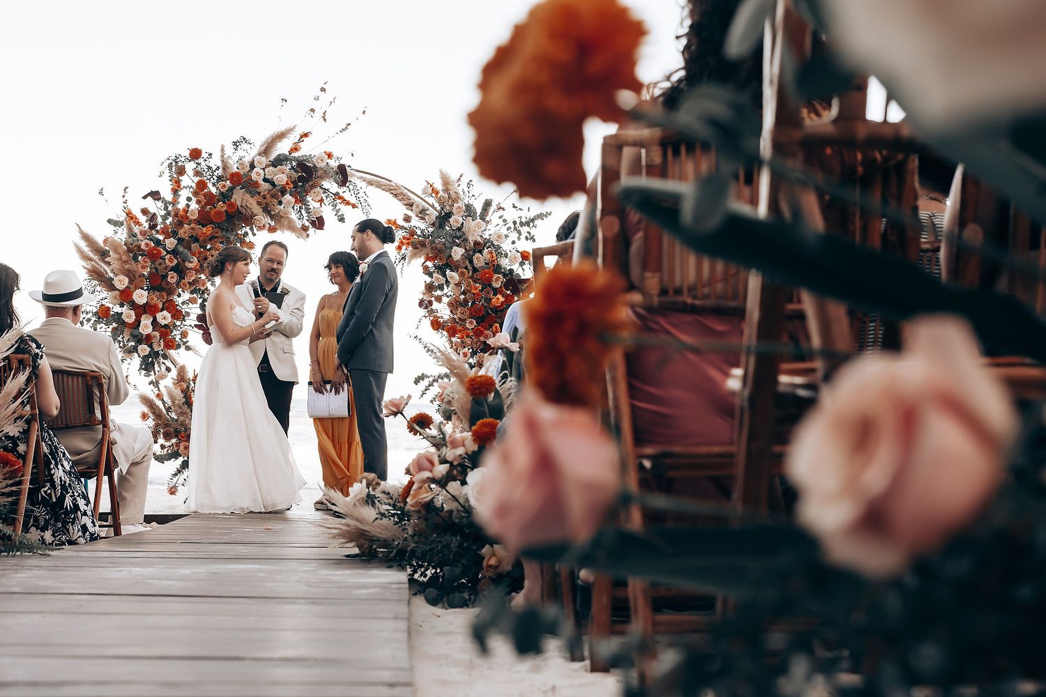 Wedding ceremony decor with orange and rust colored floral arrangements.