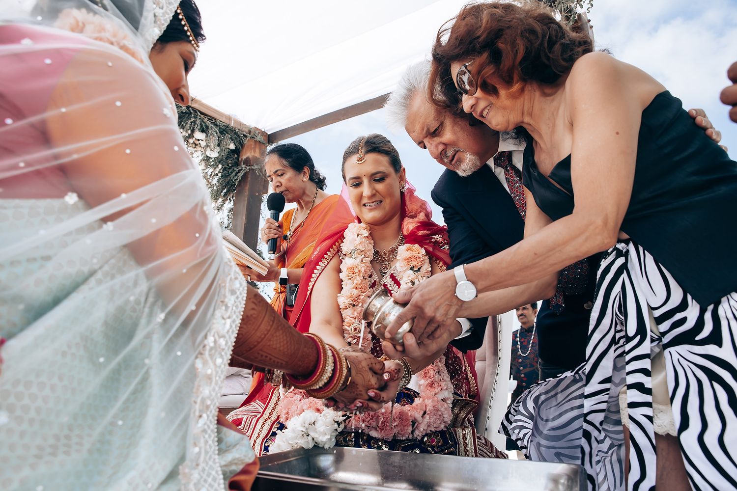 Wedding guests gather around a table participating in traditional Indian ceremony rituals.