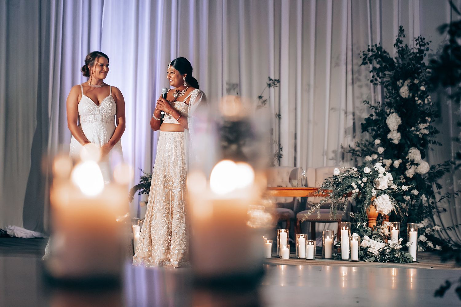 Wedding celebration with elegant white dresses and candlelit decorations.