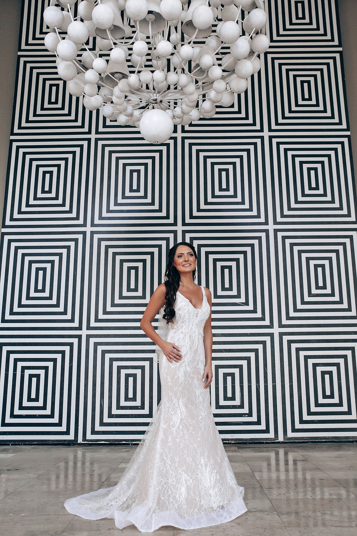 Elegant bridal portrait against geometric black and white wall with hanging white globe lights.