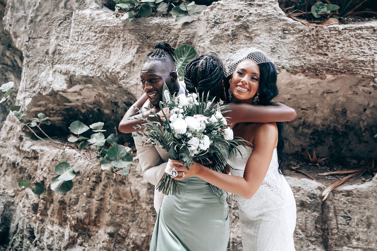 Wedding couple embracing against a rocky backdrop with white floral bouquet.