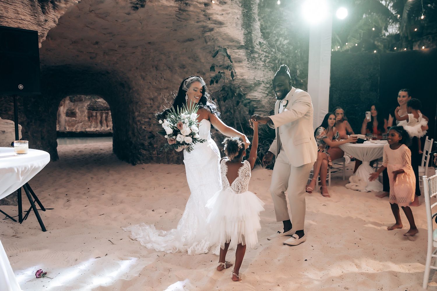 Wedding party dancing and celebrating in an atmospheric cave setting.