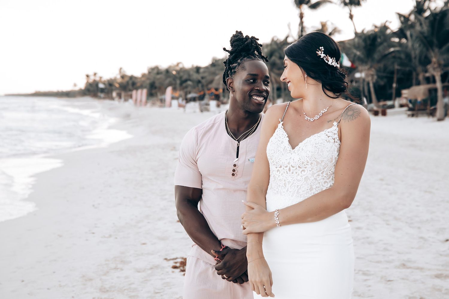 The image shows a bride and groom embracing on a tropical beach.