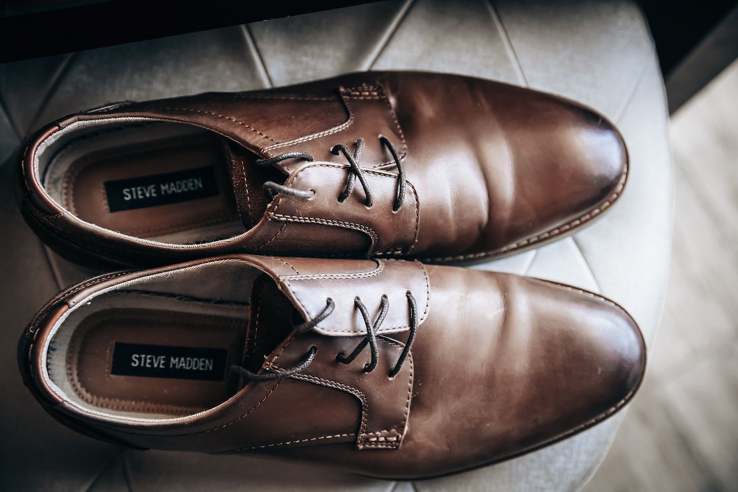 A pair of brown leather dress shoes on a wooden surface.