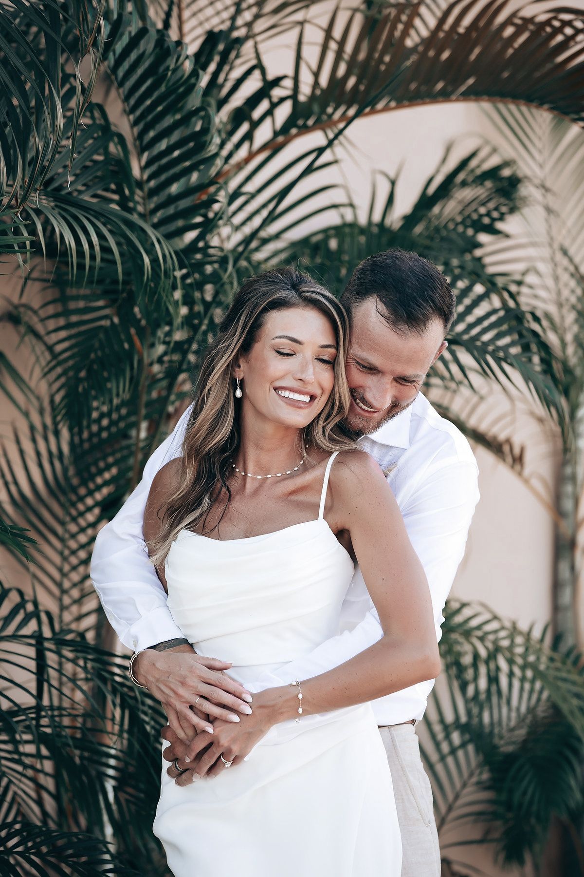 A bride and groom embracing and smiling at what appears to be an outdoor wedding or event.
