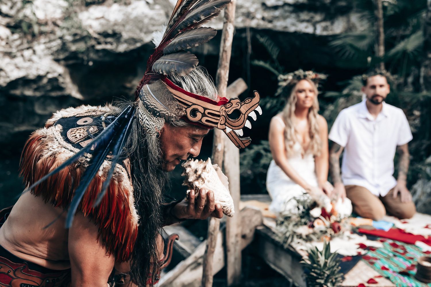 Forest wedding ceremony featuring traditional dancers in vibrant red feathered headdresses.