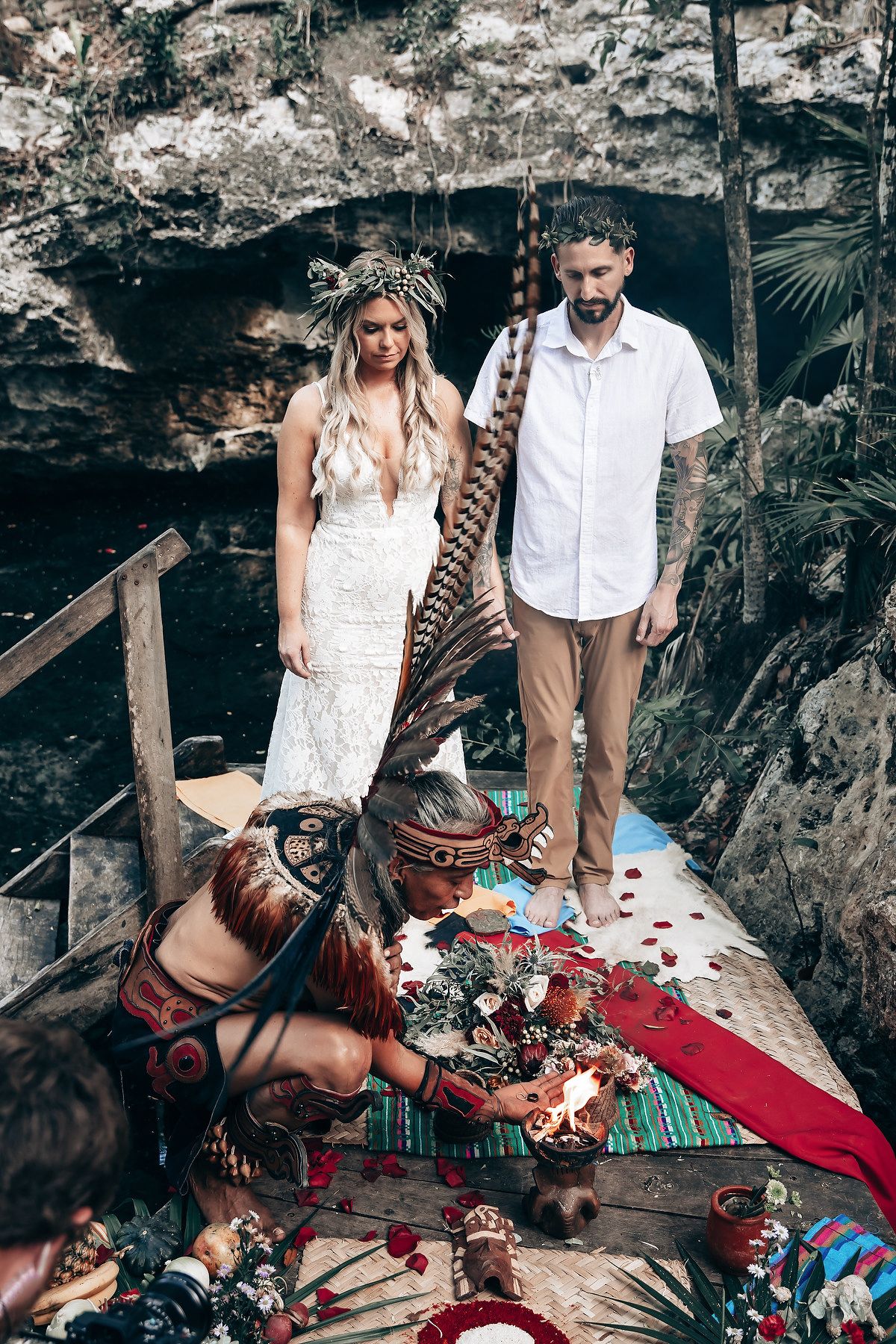 Intimate wedding ceremony in a forest cave with traditional ceremonial elements and red textiles.