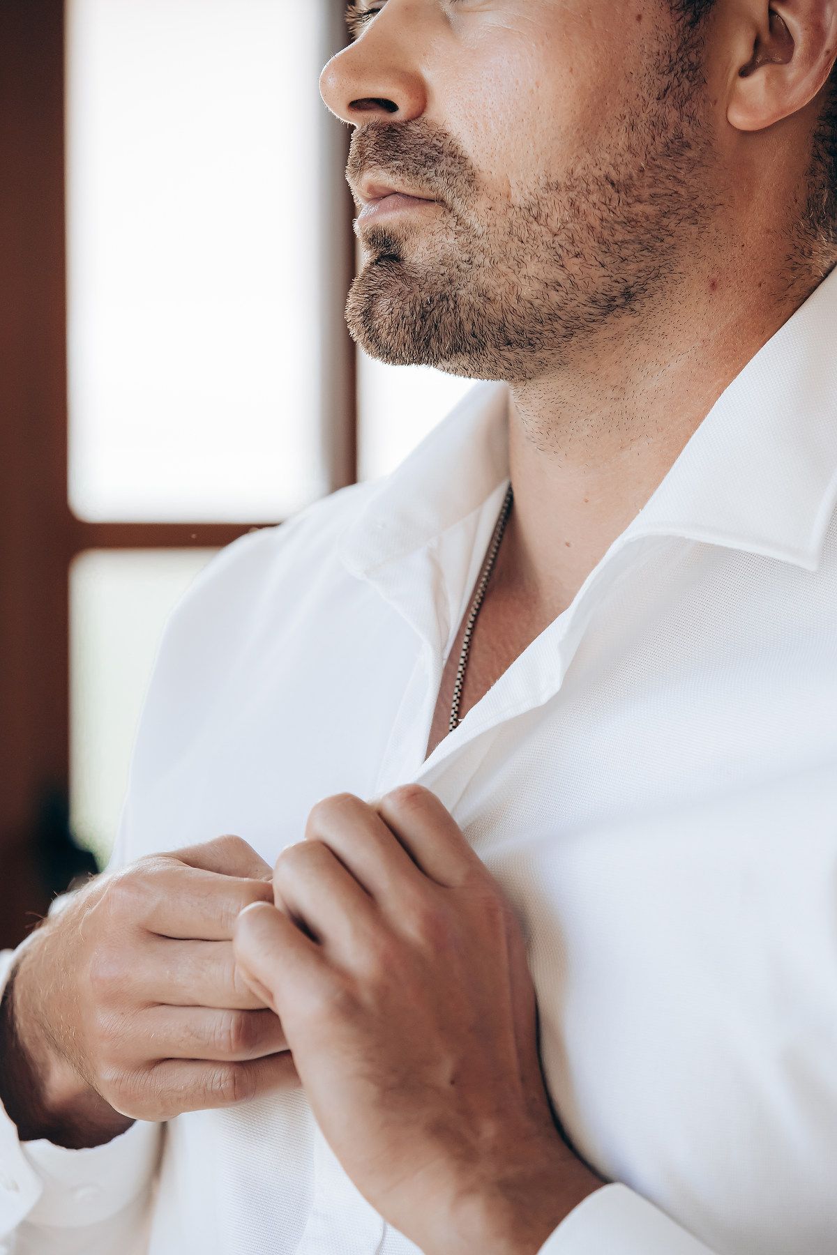 A person in a white dress shirt adjusts their collar in a sequence of close-up shots.