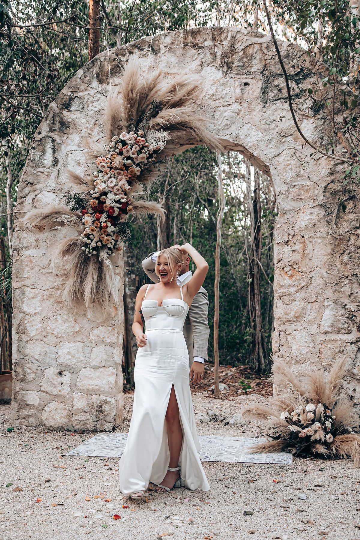 A wedding dress photoshoot in a rustic stone archway surrounded by trees and natural light.