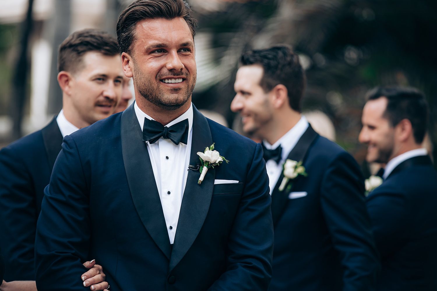 A group of people in formal black tuxedos gather together at a wedding celebration.