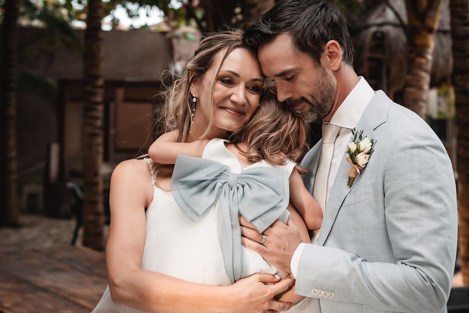 A romantic moment between newlyweds in formal attire against a tropical backdrop.