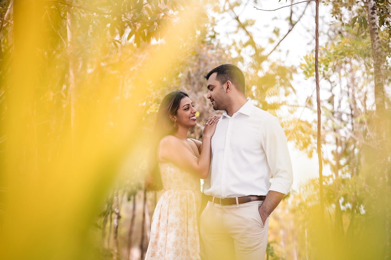 Romantic couple embraces in a sun-drenched garden with golden light filtering through trees.