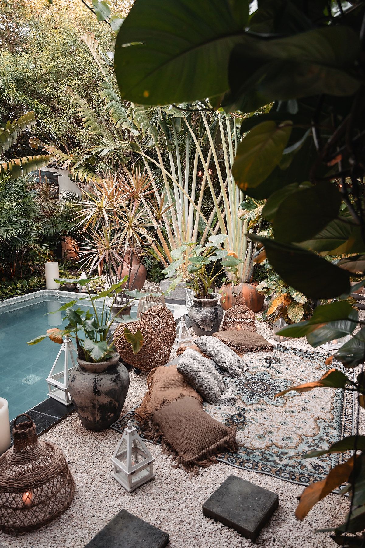 Decorative garden space featuring stone sculptures and tropical foliage around a swimming pool.