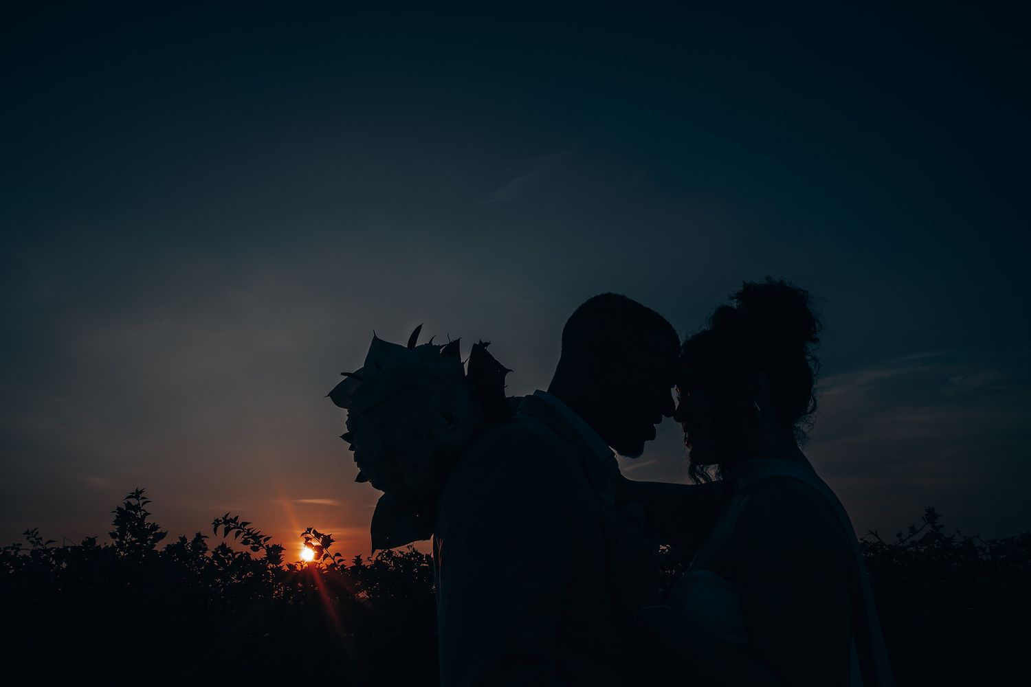 Dramatic sunset silhouettes against a dark sky create a romantic atmosphere at an outdoor event.