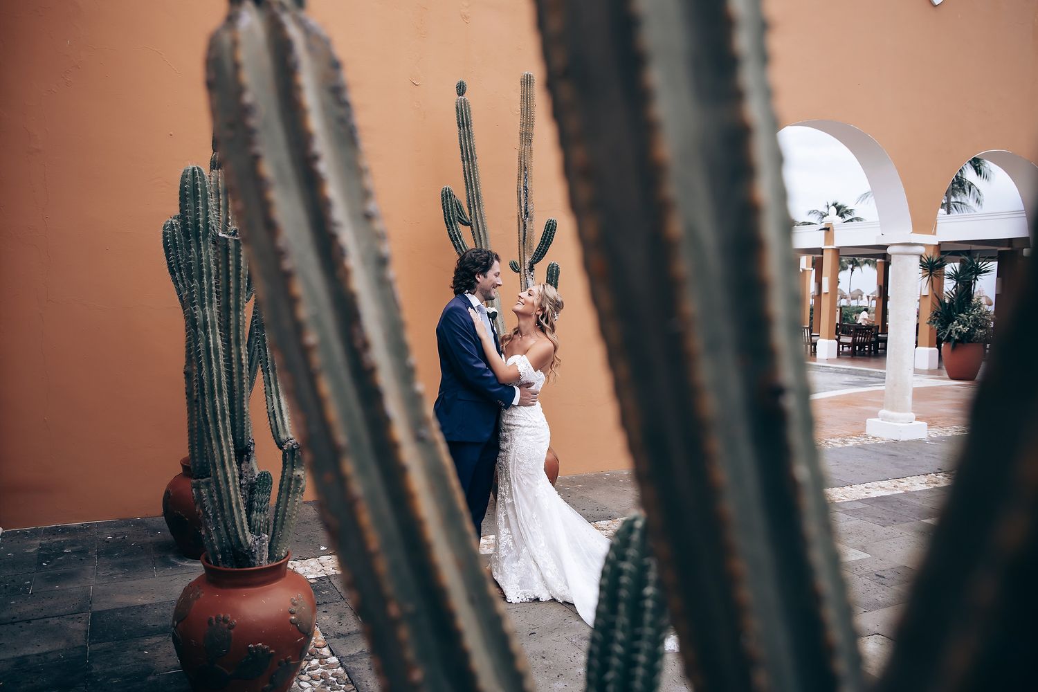 Desert wedding scene framed by dramatic cactus silhouettes against terracotta walls.
