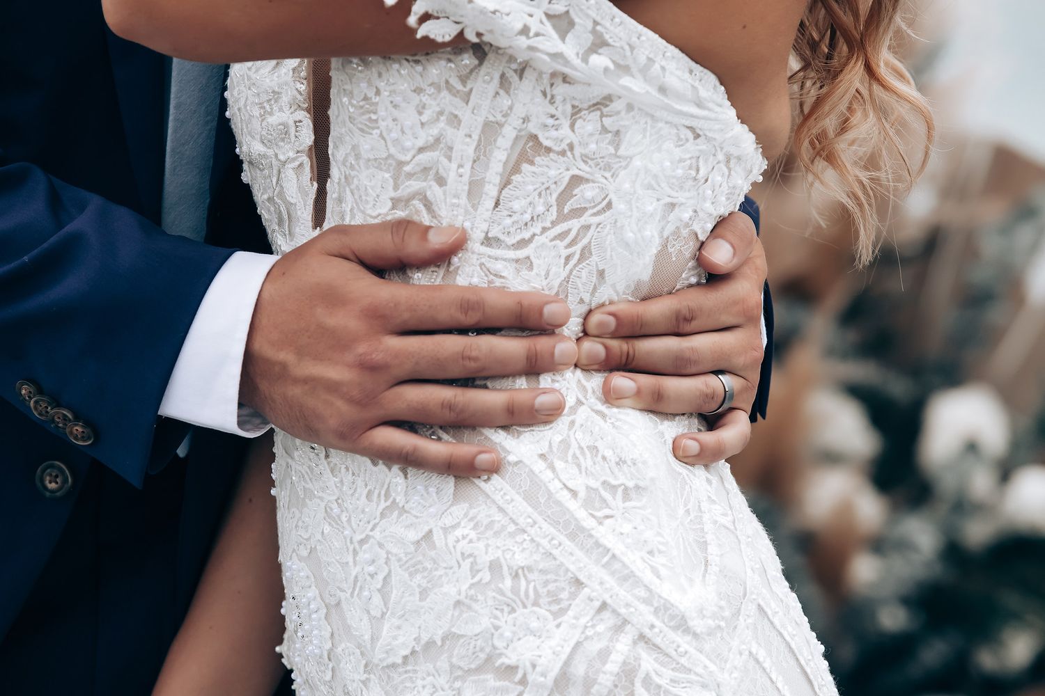 Close-up detail of intricate lace pattern on a white wedding dress.