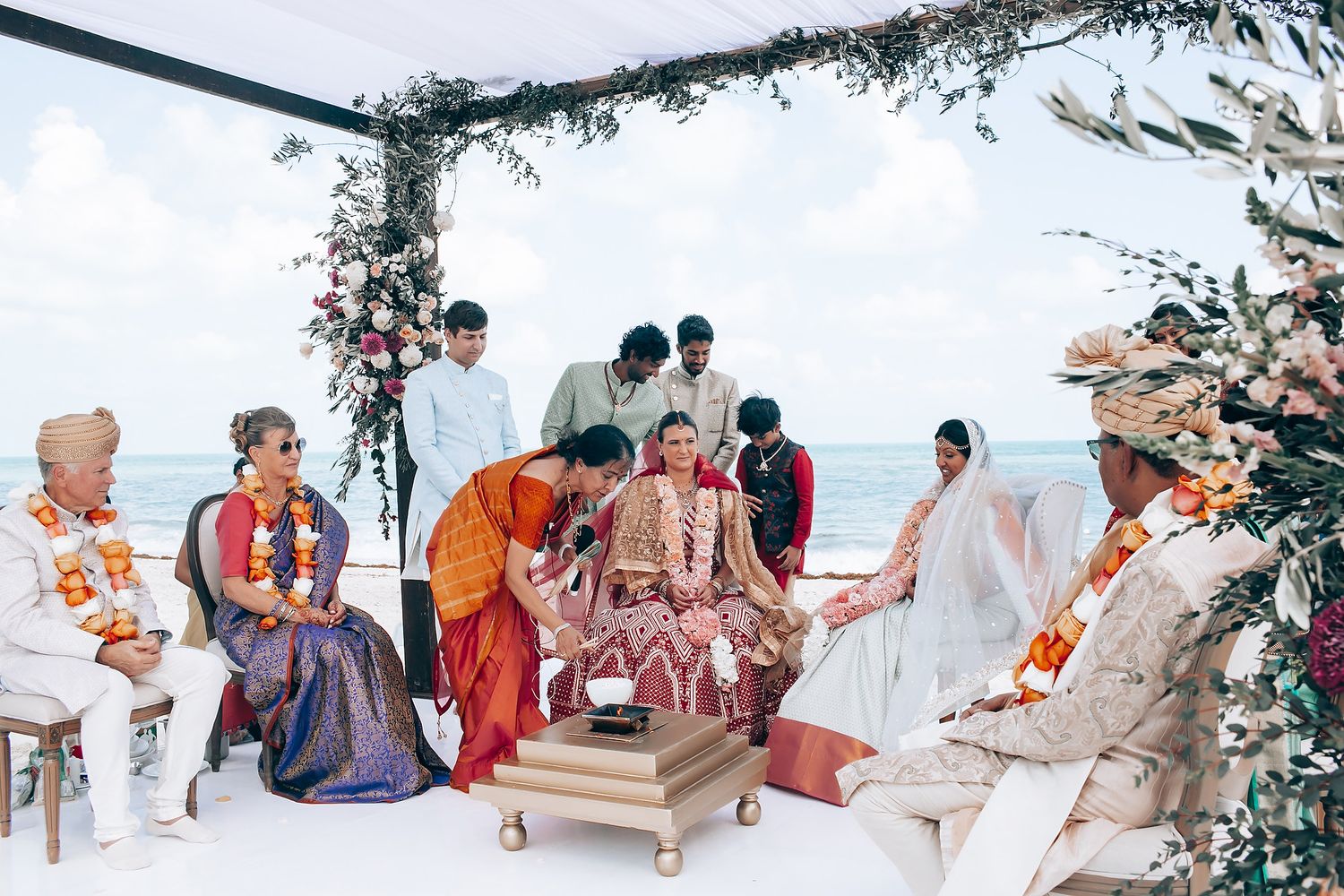Traditional Indian wedding ceremony taking place under decorated mandap by the beach.