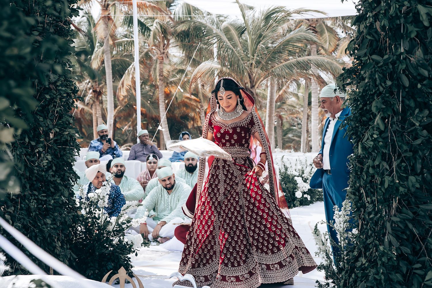 Elegant outdoor wedding venue with palm trees and white floral arrangements.