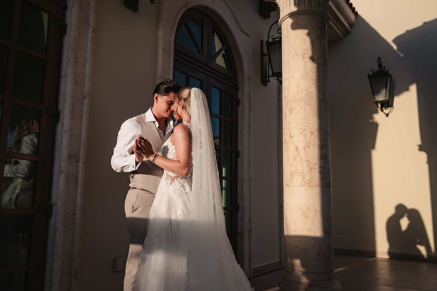 Mediterranean-style architecture frames romantic wedding portraits in warm afternoon light.