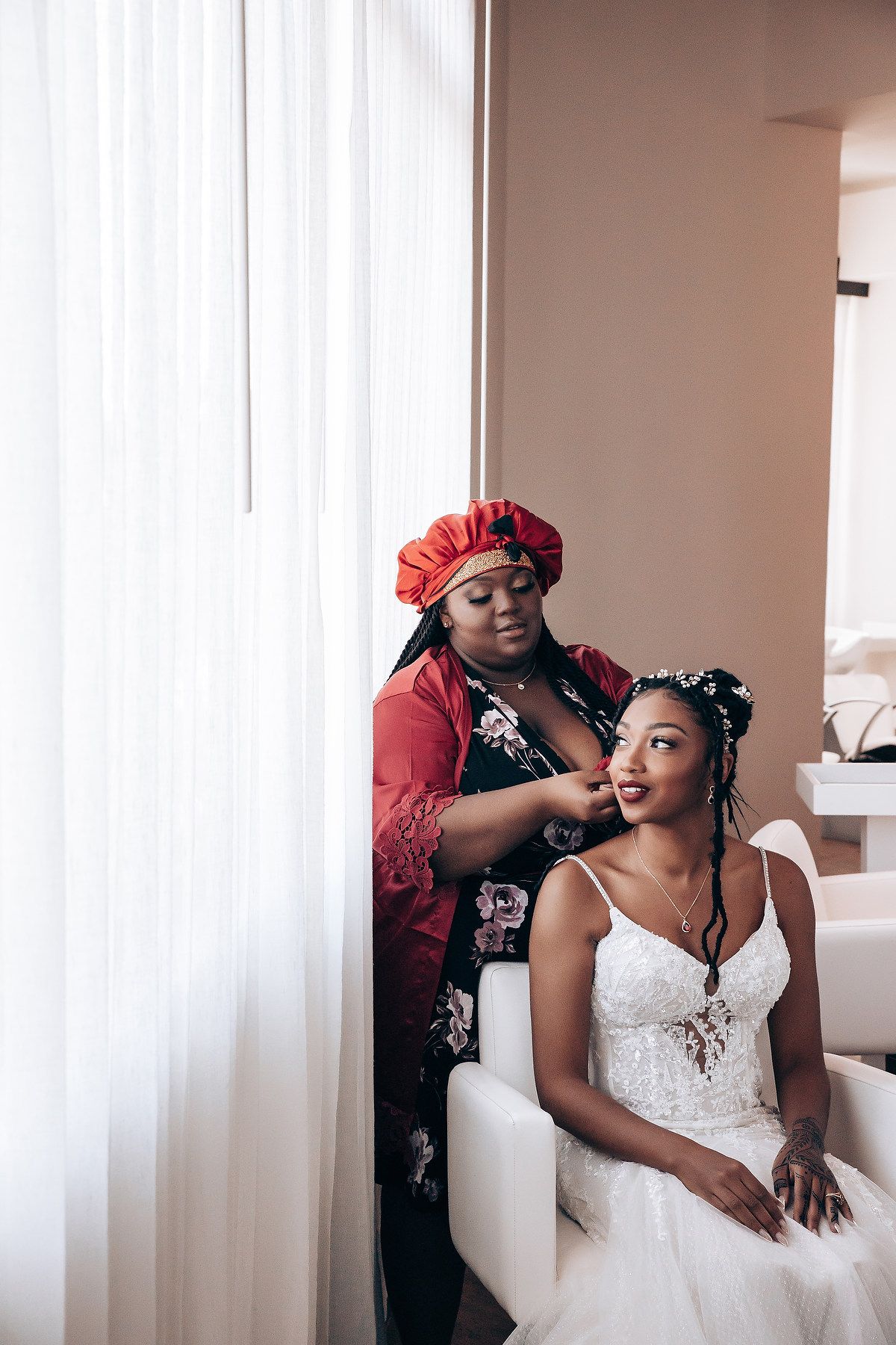 A touching moment during wedding preparations as final touches are made to the bride's elegant white dress.