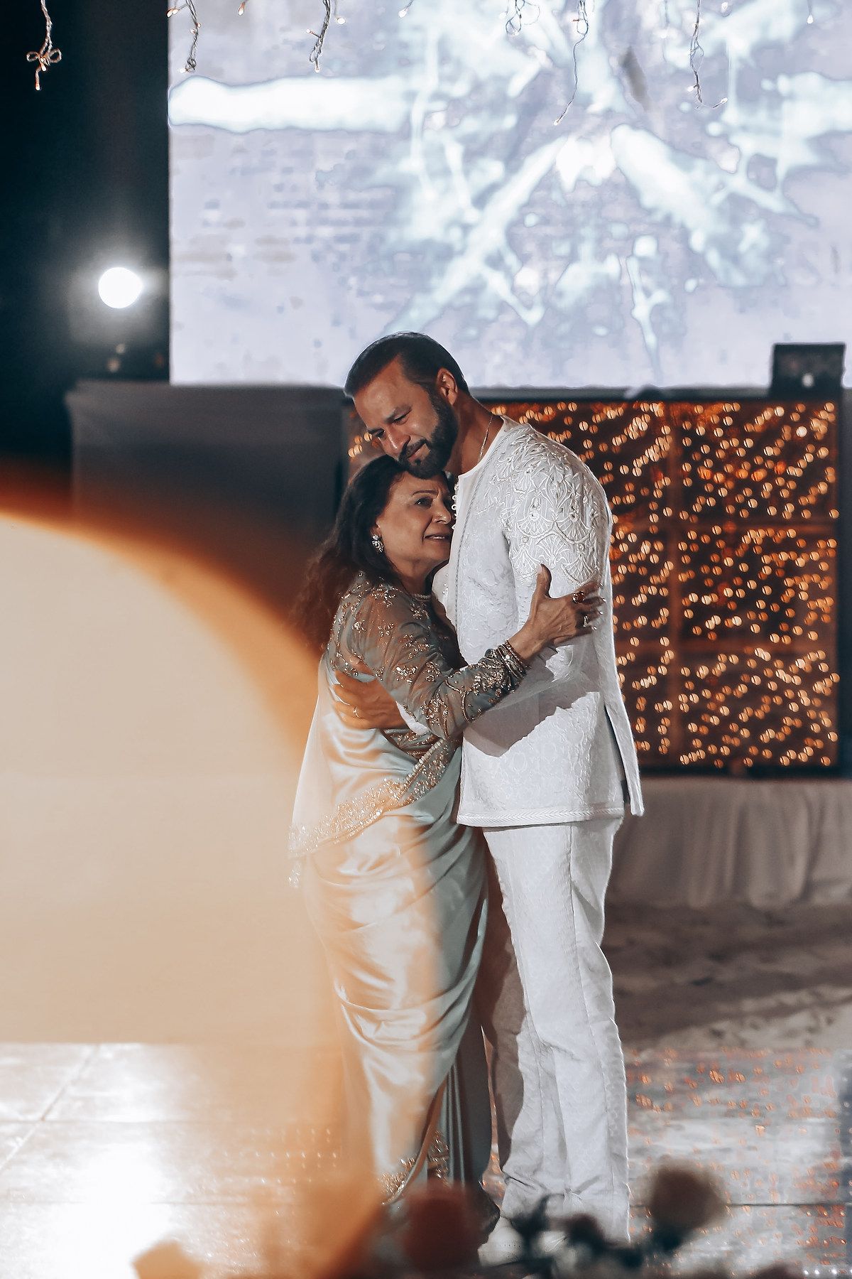 A couple shares an intimate dance moment under twinkling lights during their wedding celebration.