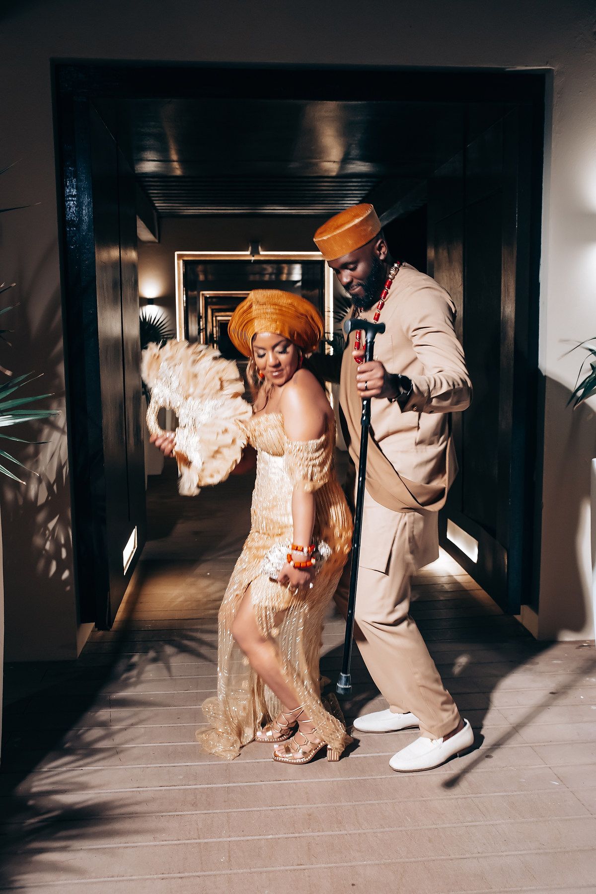 Couple in vintage-inspired attire dancing in dimly lit hallway.