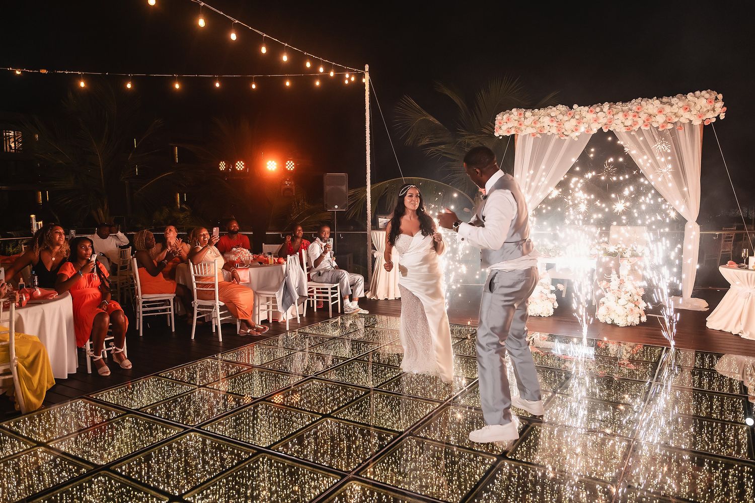 A wedding reception scene with sparklers illuminating the dance floor as guests celebrate.