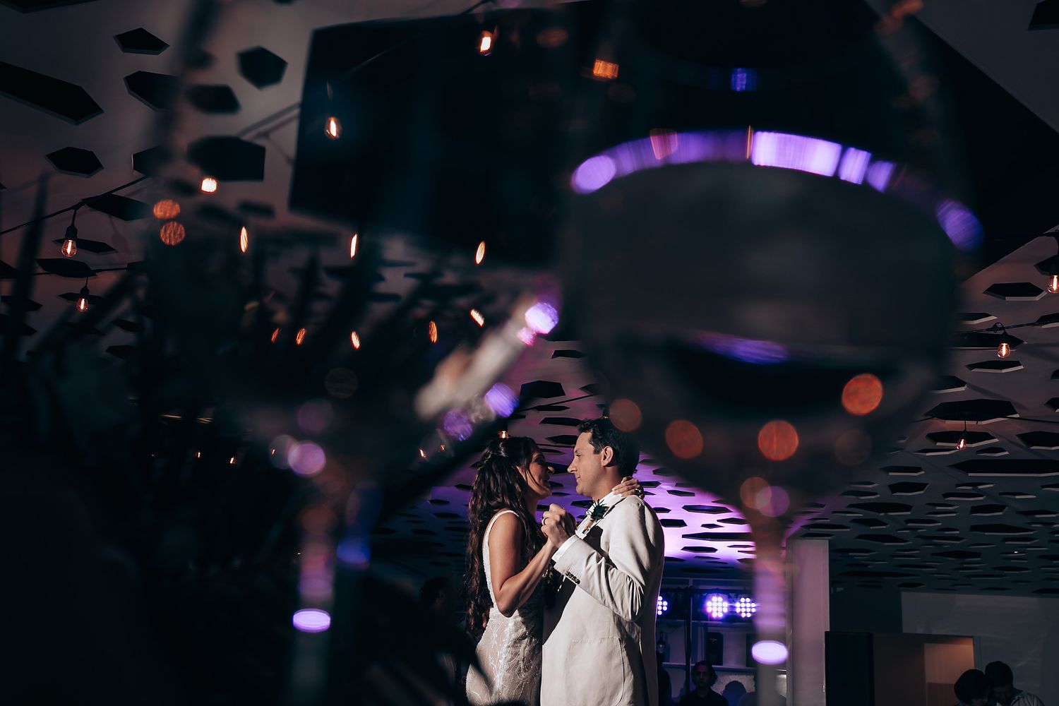 Romantic dance moment under geometric patterned ceiling with ambient purple lighting.