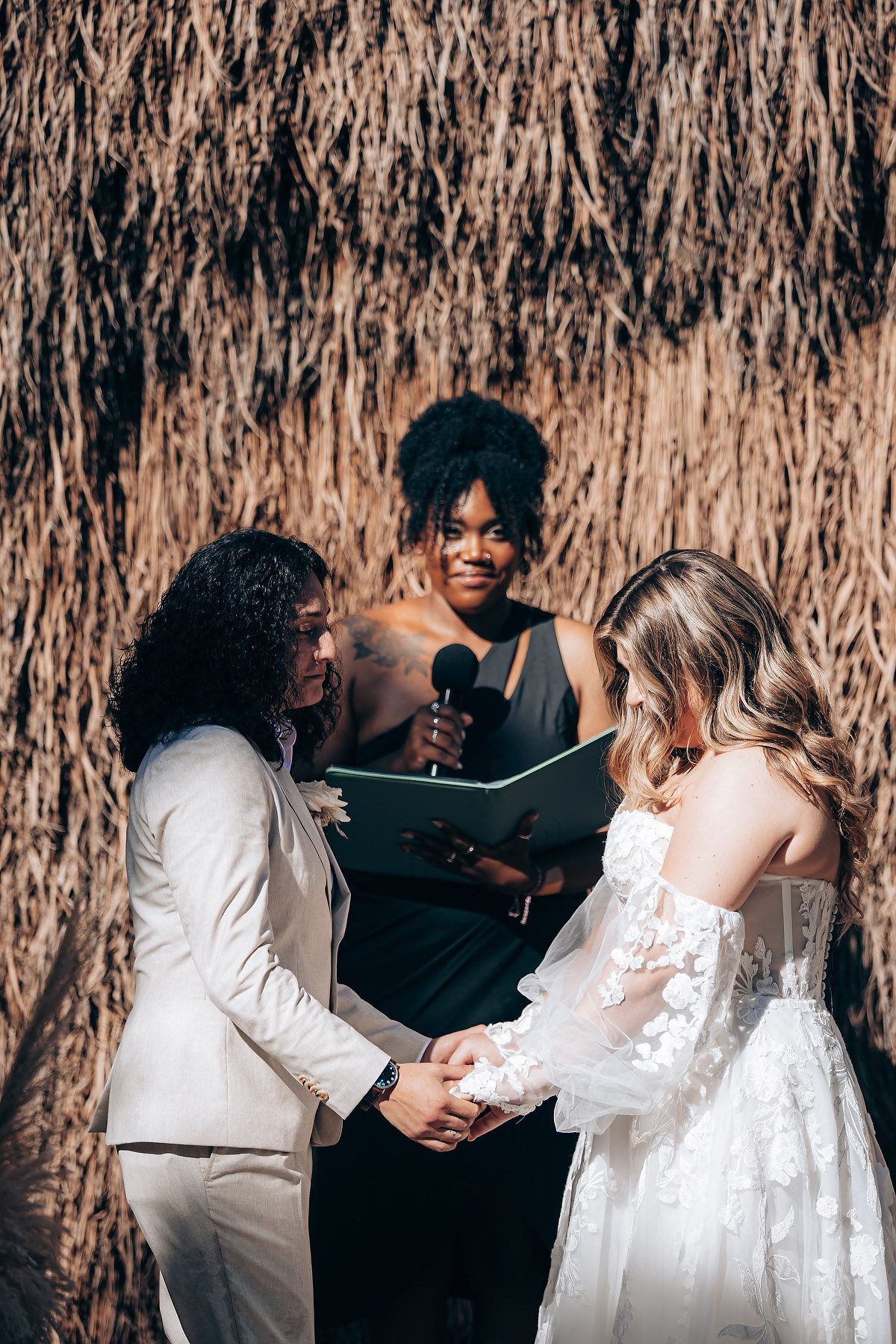 Intimate wedding celebration moment under a thatched roof canopy.