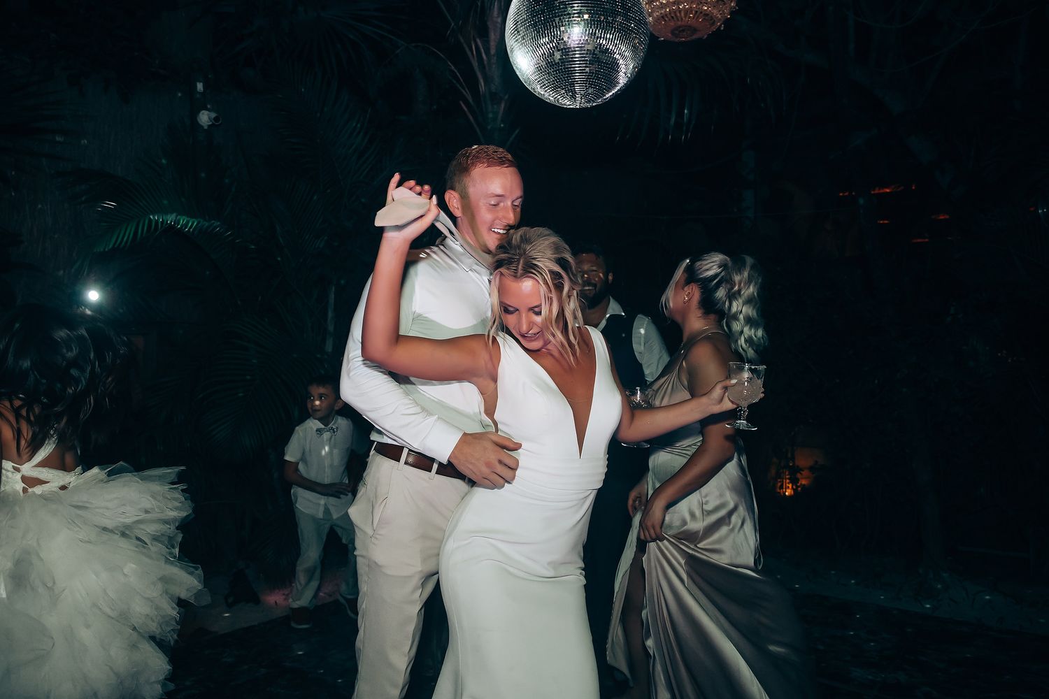 Newlyweds sharing a romantic dance moment under dim lighting at their reception.