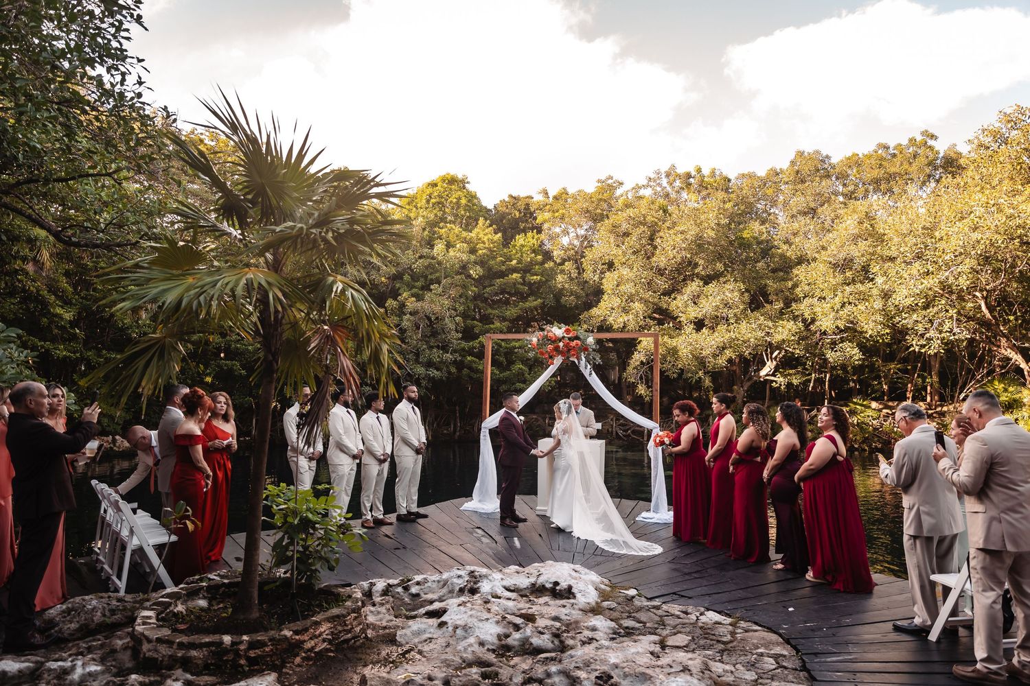 Panoramic view of outdoor wedding ceremony with bridal party in burgundy and white.