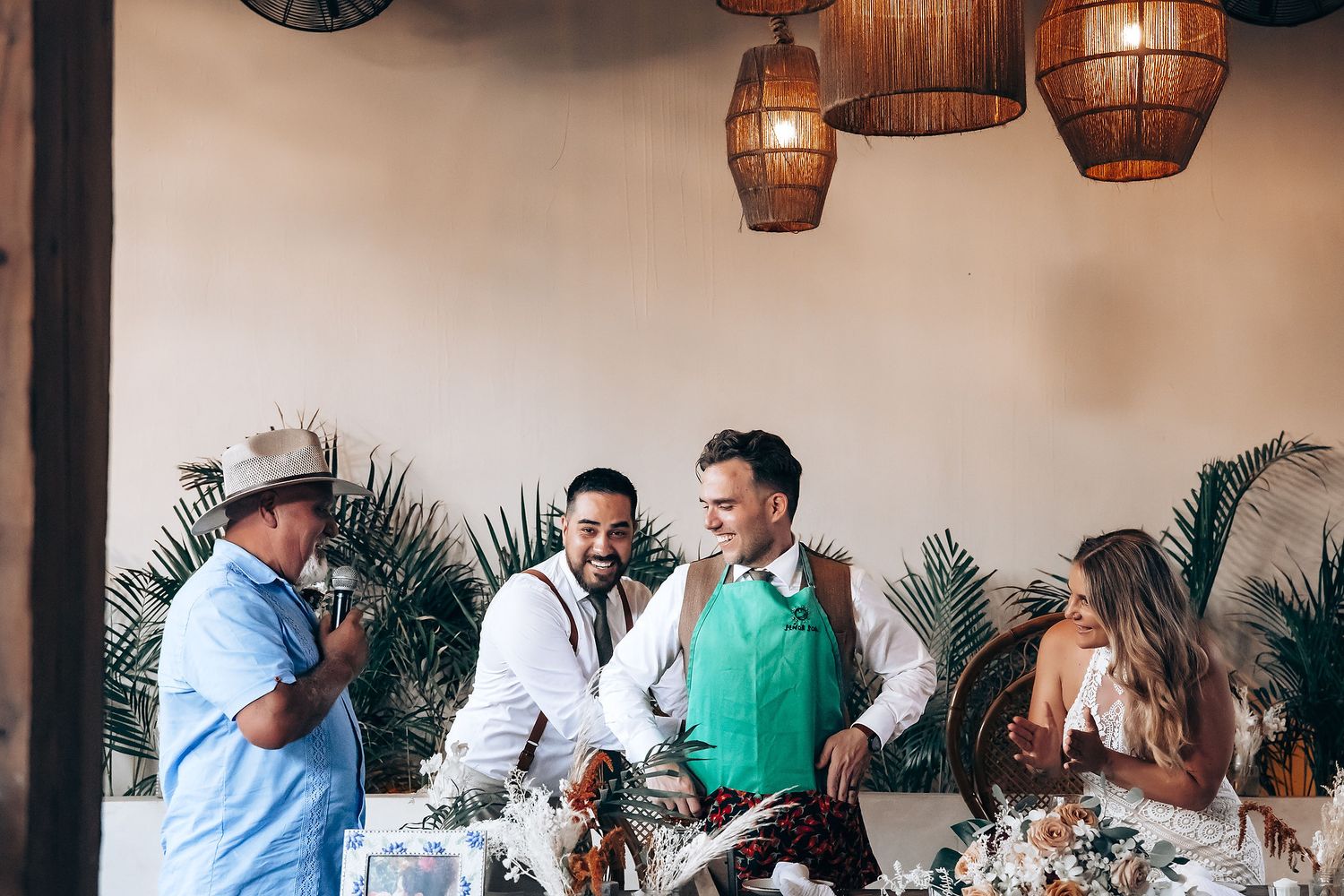 A group of people dining together at a restaurant with wooden barrel decor and palm plants in the background.