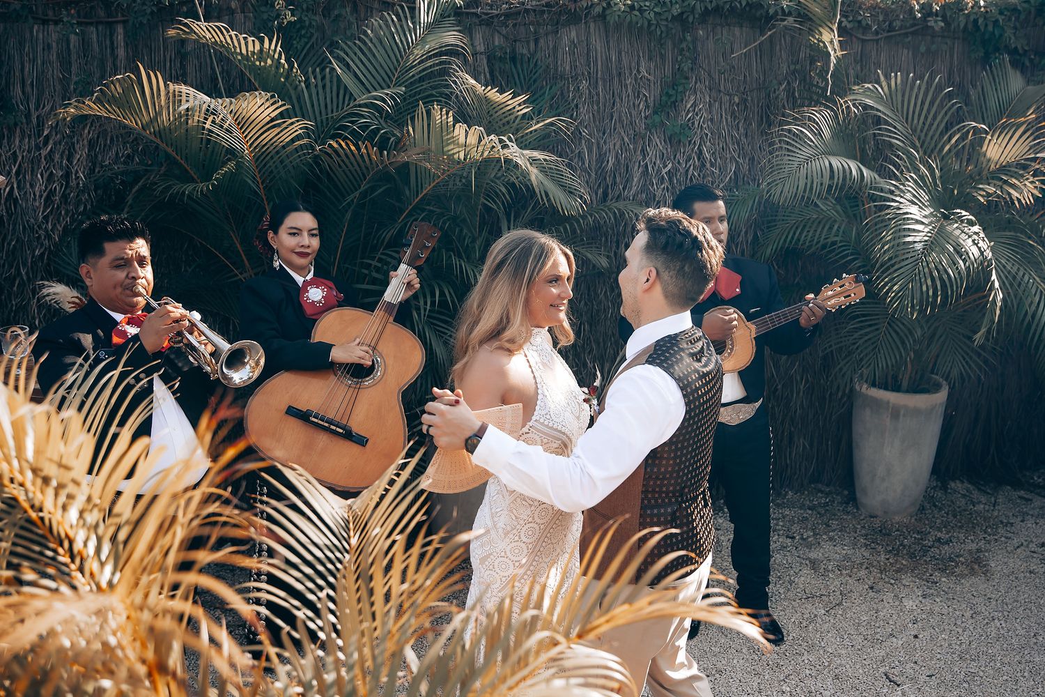 People enjoying a lively outdoor gathering with tropical plants and string lights creating an intimate atmosphere.